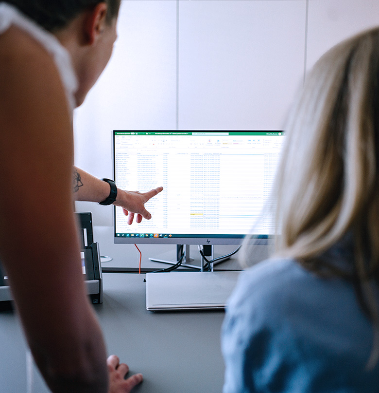 Personen vor einem Monitor die zusammen eine Auswertung bearbeiten